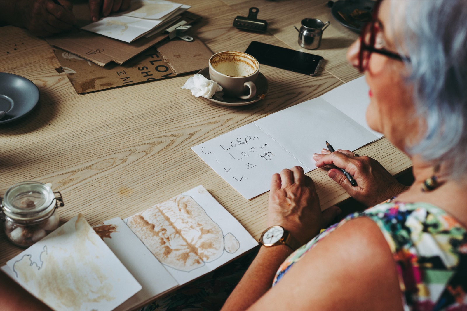 A guest sketching at a wooden table during a creative workshop